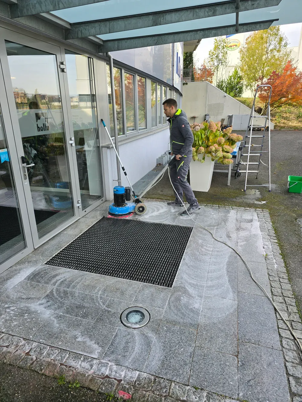 Sebastian Just reinigt einen Eingangsbereich mit einer Einscheibenmaschine
